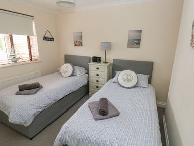 A bedroom with two single beds bedside table and lamp at Sandy Bay House in Saundersfoot