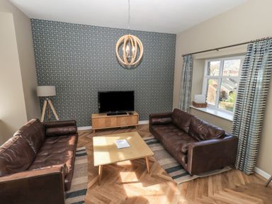 A living room with two brown leather sofas a wooden coffee table and a TV on a wooden stand at Loughrigg View in Ambleside