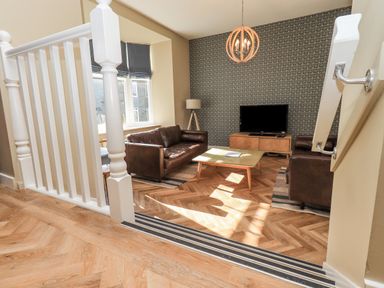 A living room with two brown leather sofas a wooden coffee table and a television on a wooden stand at Loughrigg View in Ambleside