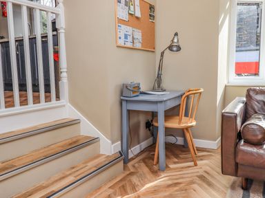 A small desk with a chair and lamp next to a staircase and a window in a living room at Loughrigg View Ambleside