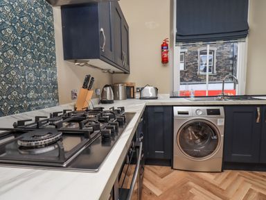 A kitchen with a gas stove washing machine sink and cabinets at Loughrigg View in Ambleside