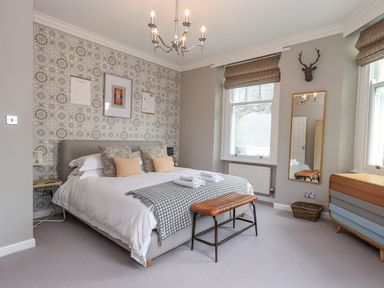 A bedroom with a bed and patterned wallpaper at Loughrigg View in Ambleside