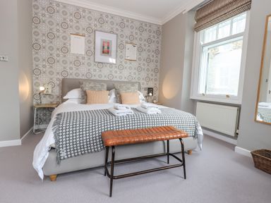 A bedroom with a bed pillows lamps window and bench at Loughrigg View in Ambleside