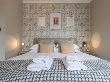 A bedroom with a double bed pillows towels bedside tables and lamps at Loughrigg View in Ambleside