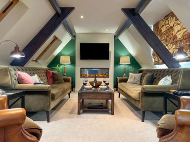 A sitting room with two sofas a coffee table with wine glasses a television and lamps at Geltsdale East Wing in Wetheral