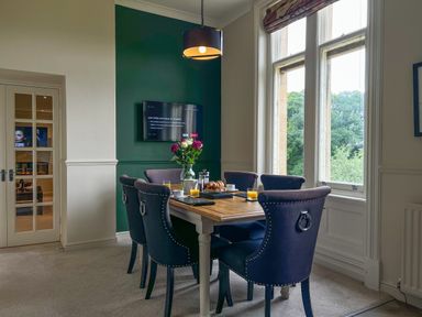 A dining room with a wooden table set for breakfast and blue chairs at Geltsdale East Wing in Wetheral