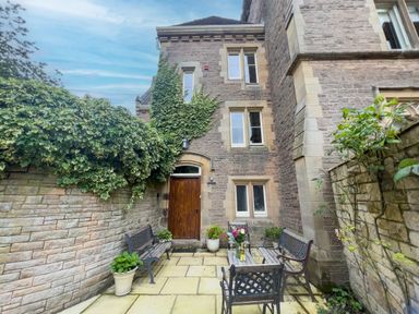 A stone courtyard with benches a table potted plants and ivy on walls at Geltsdale East Wing in Wetheral