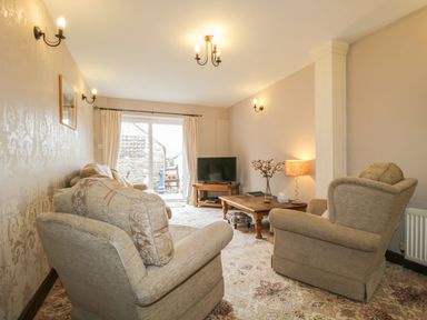 A living room with armchairs a wooden coffee table and a television at Springarth Cottage in Newby
