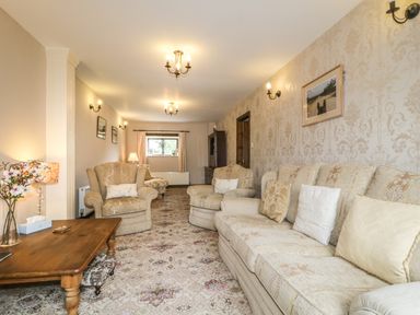 A living room with armchairs a sofa a wooden coffee table and floral carpet at Springarth Cottage in Newby