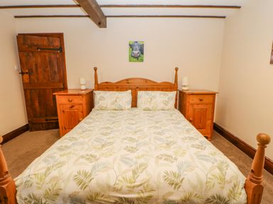 A bedroom with a wooden double bed and matching bedside tables with lamps at The Old Byre in Appleby-in-Westmorland