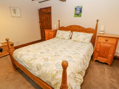 A bedroom with a wooden bed and two wooden bedside tables at The Old Byre in Appleby-in-Westmorland