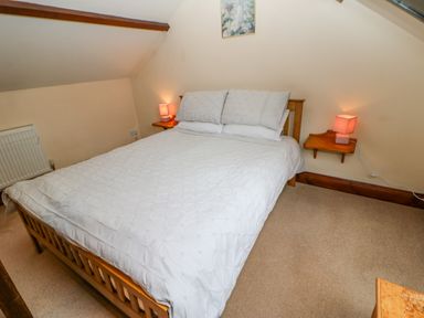 A bedroom with a double bed white bedding two bedside tables with lamps and a radiator at The Old Byre in Appleby-in-Westmorland
