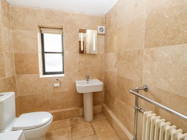 A bathroom with a toilet sink mirror window and radiator at The Old Byre in Appleby-in-Westmorland