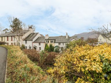 A row of houses behind a garden with shrubs and a pathway on the left at Derwent Edge in Portinscale