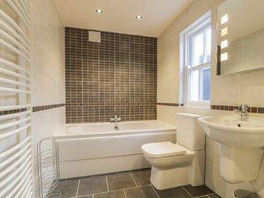 A bathroom with a bathtub toilet sink and a window at Wrenville in Keswick