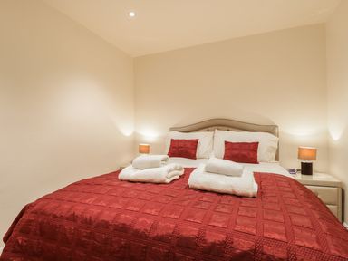 A bedroom with a double bed red bedspread and two bedside tables with lamps at Wrenville in Keswick