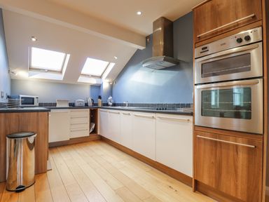 A kitchen with wooden floor skylights double ovens and white cabinets at Wrenville in Keswick