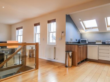 An open kitchen and living area with wooden floor and glass staircase railing at Wrenville in Keswick
