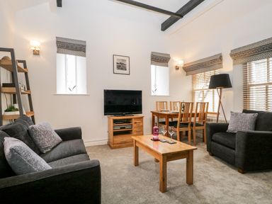 A living room with sofas coffee table television dining table and chairs at The Old Hayloft in Keswick
