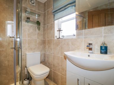 A bathroom with a toilet shower sink and window with a roller blind at The Old Hayloft in Keswick
