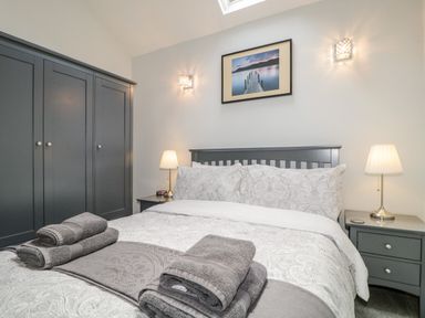 A bedroom with a bed bedside tables lamps and a wardrobe at The Old Hayloft in Keswick