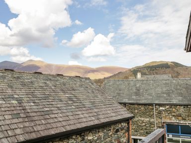Stone buildings with slate roofs and hills in the background at The Old Hayloft in Keswick