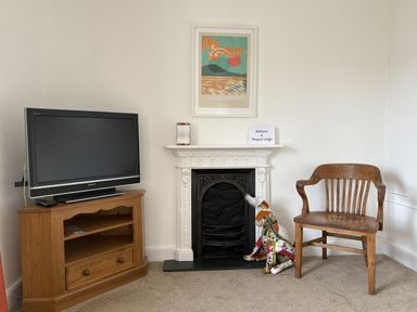 A living room with a television, chair, and fireplace at Prospect Lodge in Portinscale