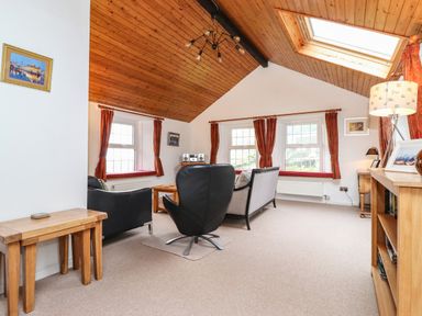A living room with armchairs sofa coffee table and wooden ceiling at Coombe Cottage in Borrowdale