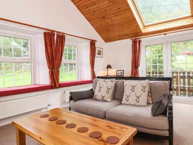 A living room with a gray sofa and wooden coffee table under a skylight at Coombe Cottage in Borrowdale