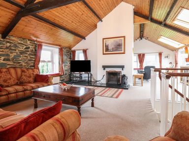 A living room with a fireplace TV couches and a wooden coffee table at Coombe Cottage in Borrowdale