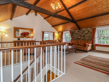 A sitting room with striped sofas a wooden coffee table and stone wall at Coombe Cottage in Borrowdale