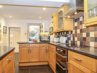 A kitchen with wooden cabinets black countertops and tiled backsplash at Coombe Cottage in Borrowdale