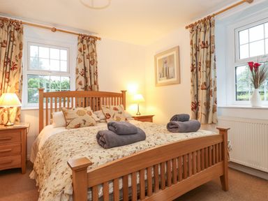 A bedroom with a wooden bed and bedside tables with lamps at Coombe Cottage in Borrowdale