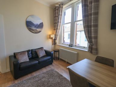 A living room with a sofa and dining table at St Johns View in Keswick