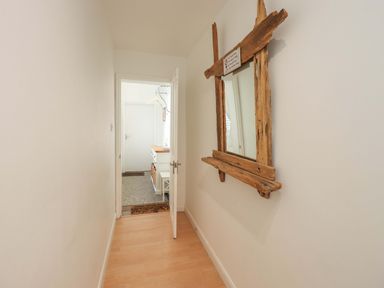 A hallway with a mirror and a door leading to another room at St Johns View in Keswick