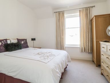 A bedroom with a double bed a window with curtains and wooden furniture at Helvellyn in Keswick