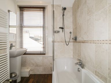 A bathroom with a bathtub shower sink window with blinds and wall tiles at Helvellyn in Keswick