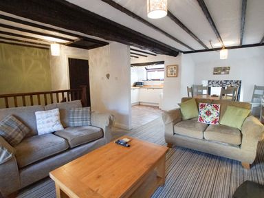 A living room with two sofas a wooden coffee table and an open kitchen at Laurel Cottage in Spark Bridge