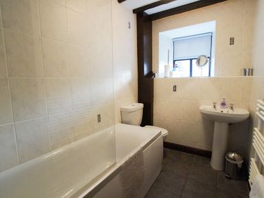 A bathroom with a bathtub sink toilet window and towel radiator at Laurel Cottage in Spark Bridge