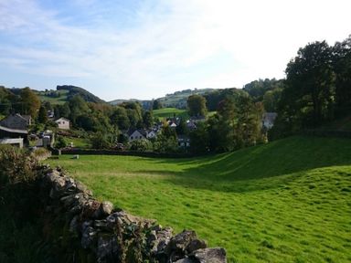 A rural landscape with green fields trees hills and houses in the distance at Laurel Cottage Spark Bridge