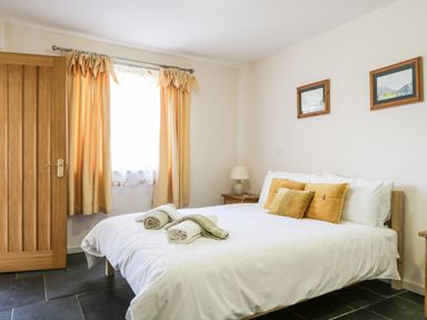 A bedroom with a bed with white sheets and yellow pillows next to a window with yellow curtains at Skiddaw in Cockermouth