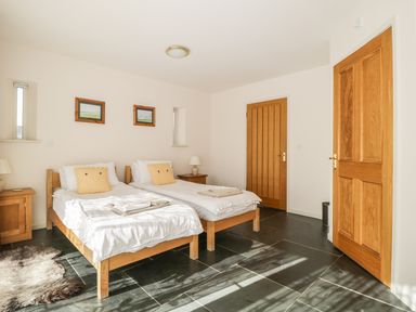 A bedroom with two single beds bedside tables lamps and framed pictures on the wall at Skiddaw in Cockermouth