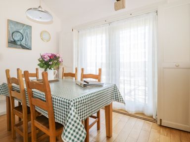 A dining room with a green checkered tablecloth on a table and wooden chairs at Skiddaw in Cockermouth