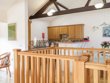 A kitchen area with wooden cabinets and a wooden railing in the foreground at Skiddaw in Cockermouth