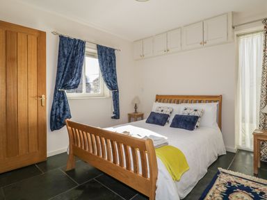 A bedroom with a wooden bed frame and blue curtains at Esthers Barn in Cockermouth