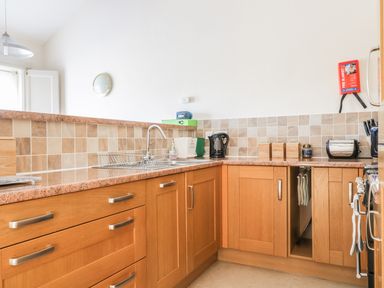 A kitchen with wooden cabinets a sink a kettle a toaster and canisters at Esthers Barn in Cockermouth