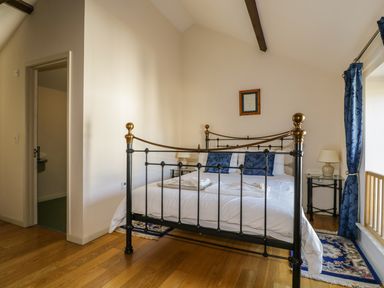A bedroom with a metal bed frame blue pillows a wooden floor and blue curtains at Beckside in Cockermouth