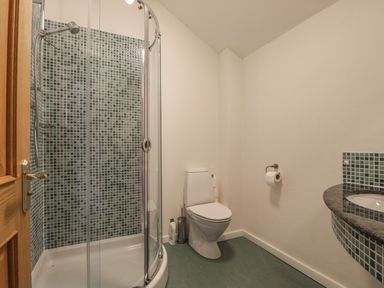 A bathroom with a glass shower, toilet, and sink with tiled backsplash at Beckside in Cockermouth