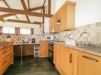 A kitchen with wooden cabinets black floor and exposed wooden beams at Buttermere in Cockermouth