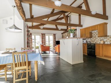 A kitchen and dining area with wooden beams and chairs and a table covered with a blue checkered tablecloth at Buttermere in Cockermouth
